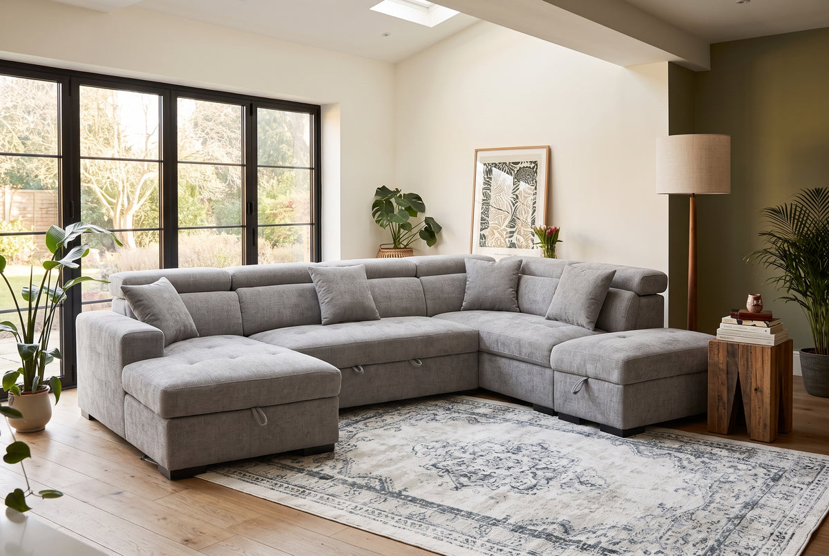 Augusta grey chenille U-shaped sofa bed with open storage compartments, pull-out bed section and adjustable headrests.
