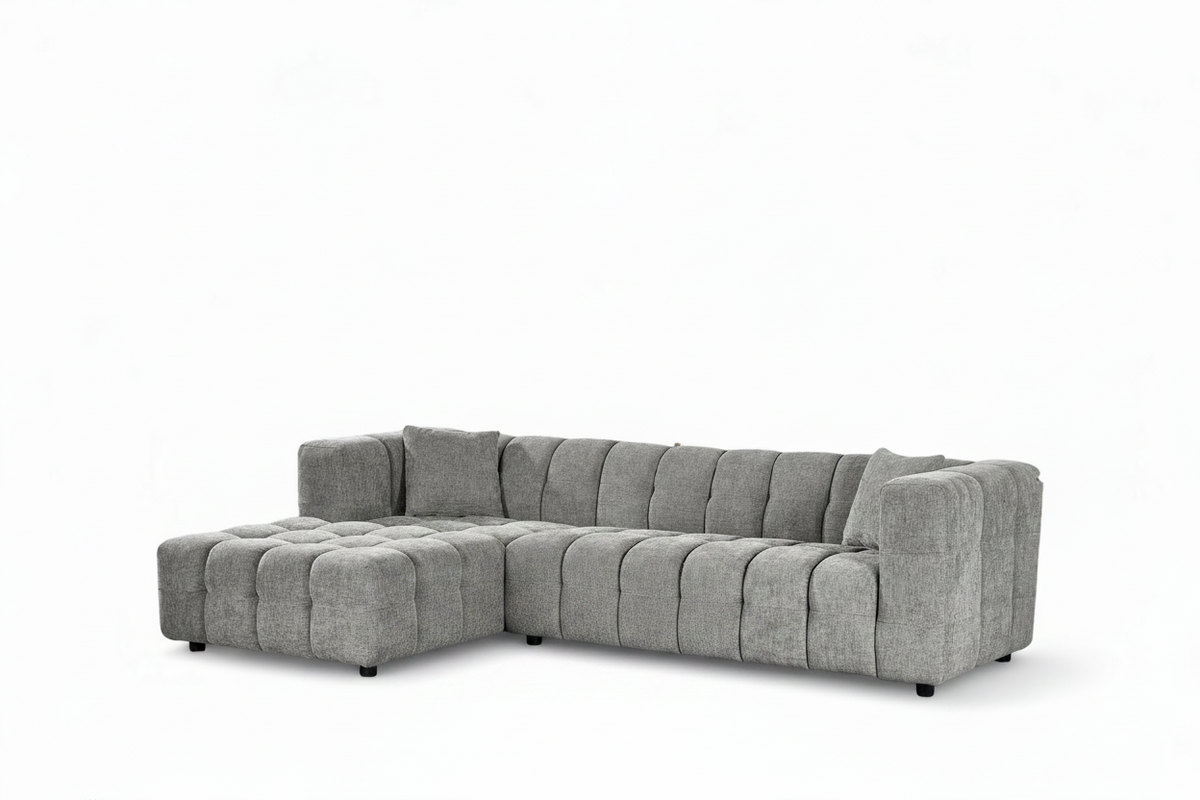 An L-shaped tufted sofa with right hand facing chaise end section, upholstered in grey chenille fabric