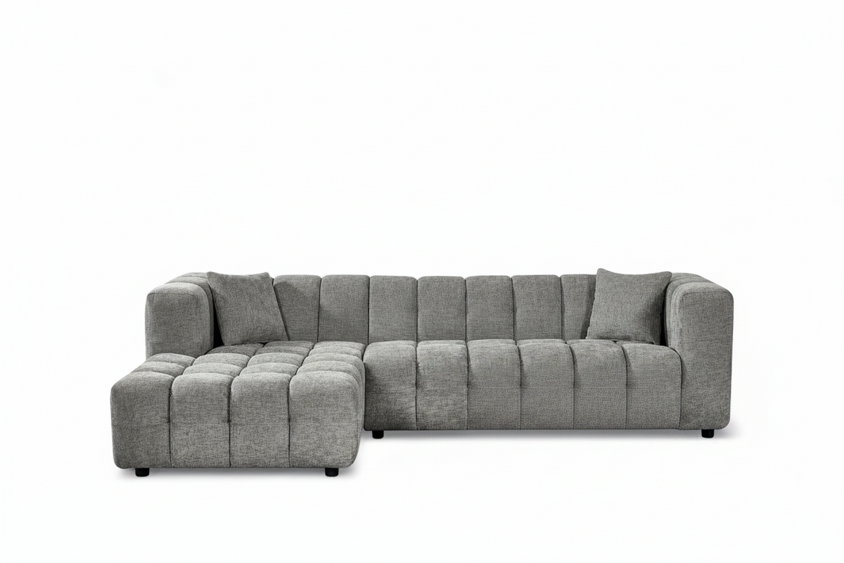 An L-shaped tufted sofa with right hand facing chaise end section, upholstered in grey chenille fabric