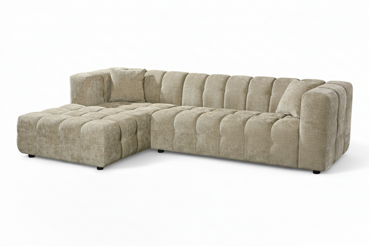 An L-shaped tufted sofa with left hand facing chaise end section, upholstered in beige chenille fabric