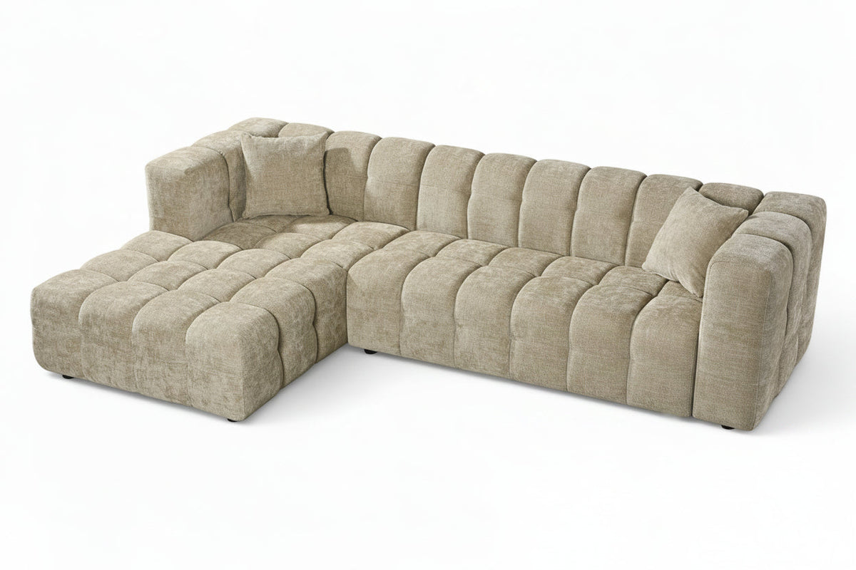 An L-shaped tufted sofa with left hand facing chaise end section, upholstered in beige chenille fabric