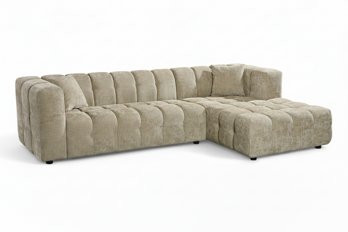 An L-shaped tufted sofa with right hand facing chaise end section, upholstered in beige chenille fabric