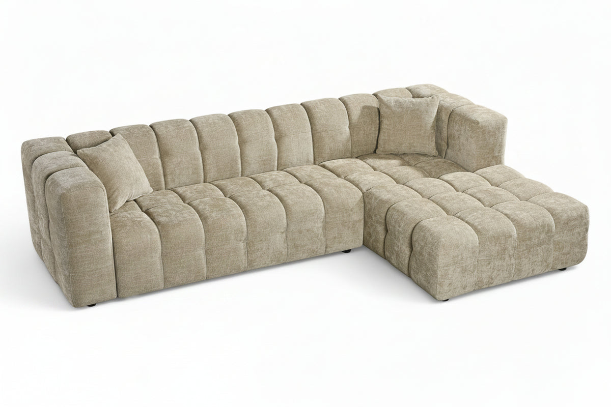 An L-shaped tufted sofa with right hand facing chaise end section, upholstered in beige chenille fabric